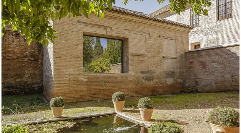 Una ventana en un jardín de la alhambra. rehabilitación de la edificación anexa al baño de la mezquita de la alhambra para espacio expositivo del legado artístico y musical de la familia barrios | Premis FAD 2022 | Interiorismo